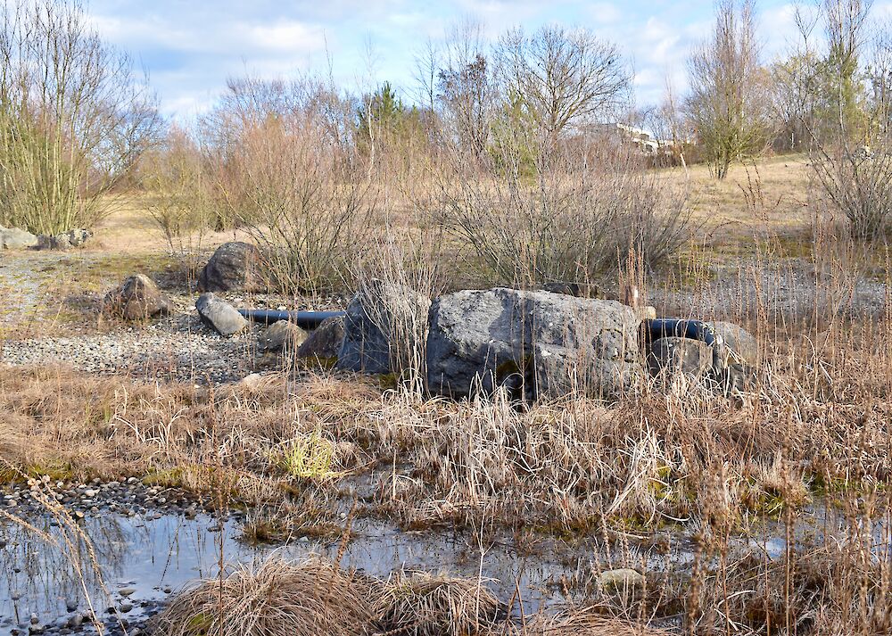 Die Röhre für das Löschwasser aus dem Tunnel ist mit Steinen und Pflanzen 